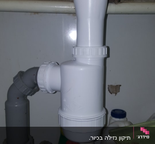 צינור פלסטיק לבן מתחת לכיור עם מחברים